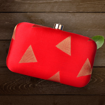 Red clutch bag with brown triangle patterns on a wooden surface