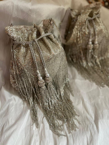 Decorative silver beaded bag with tassels on a textured white background